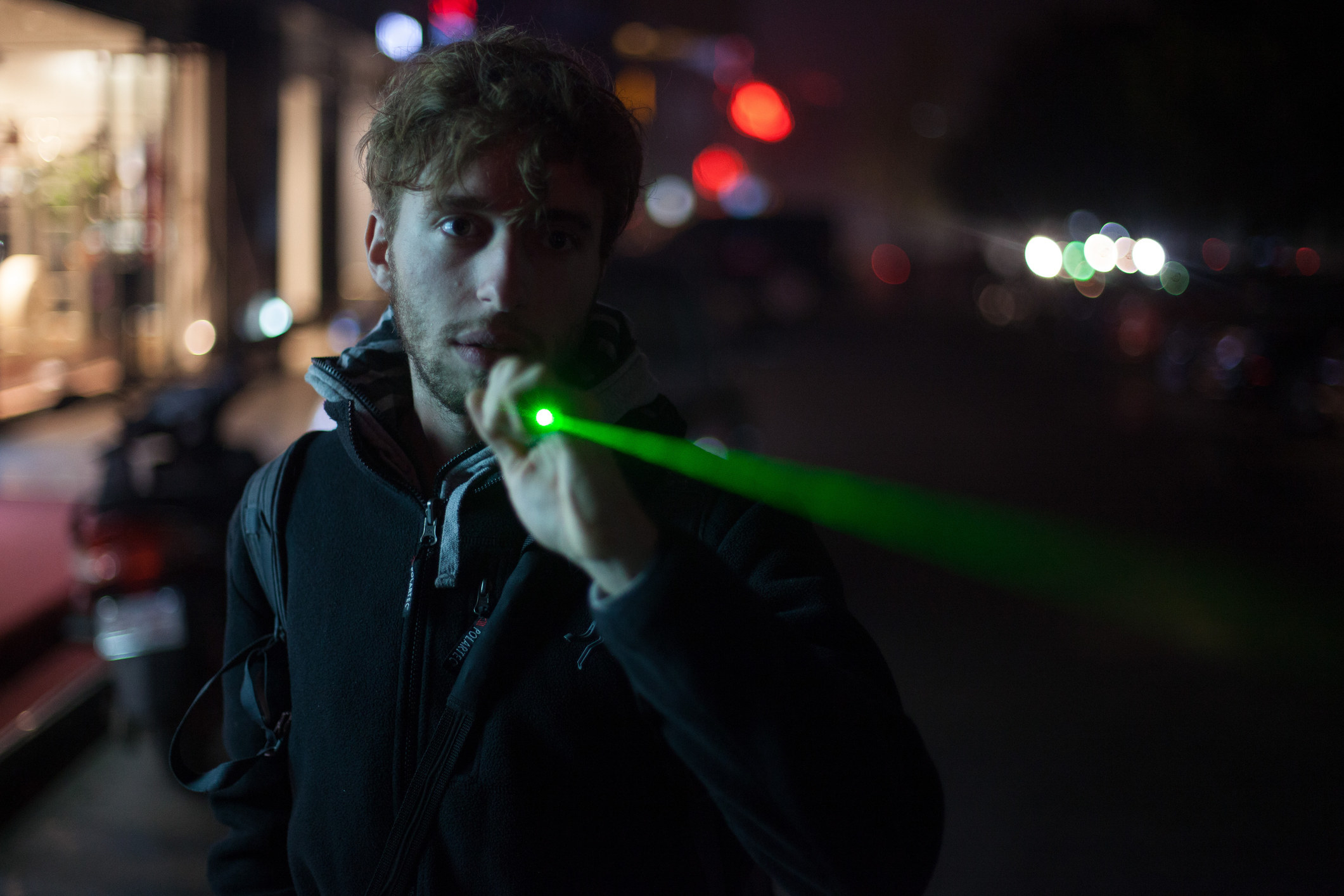 A photo of man shinning his laser pointer on the street at night