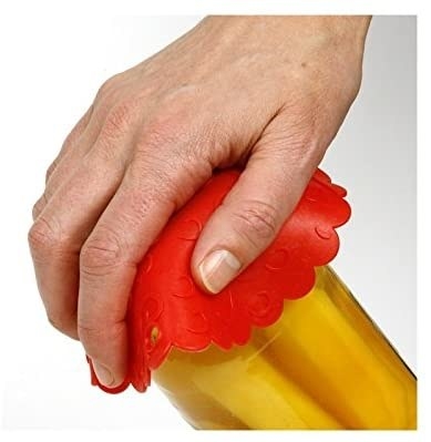 A hand uses a silicone cover to open a jar