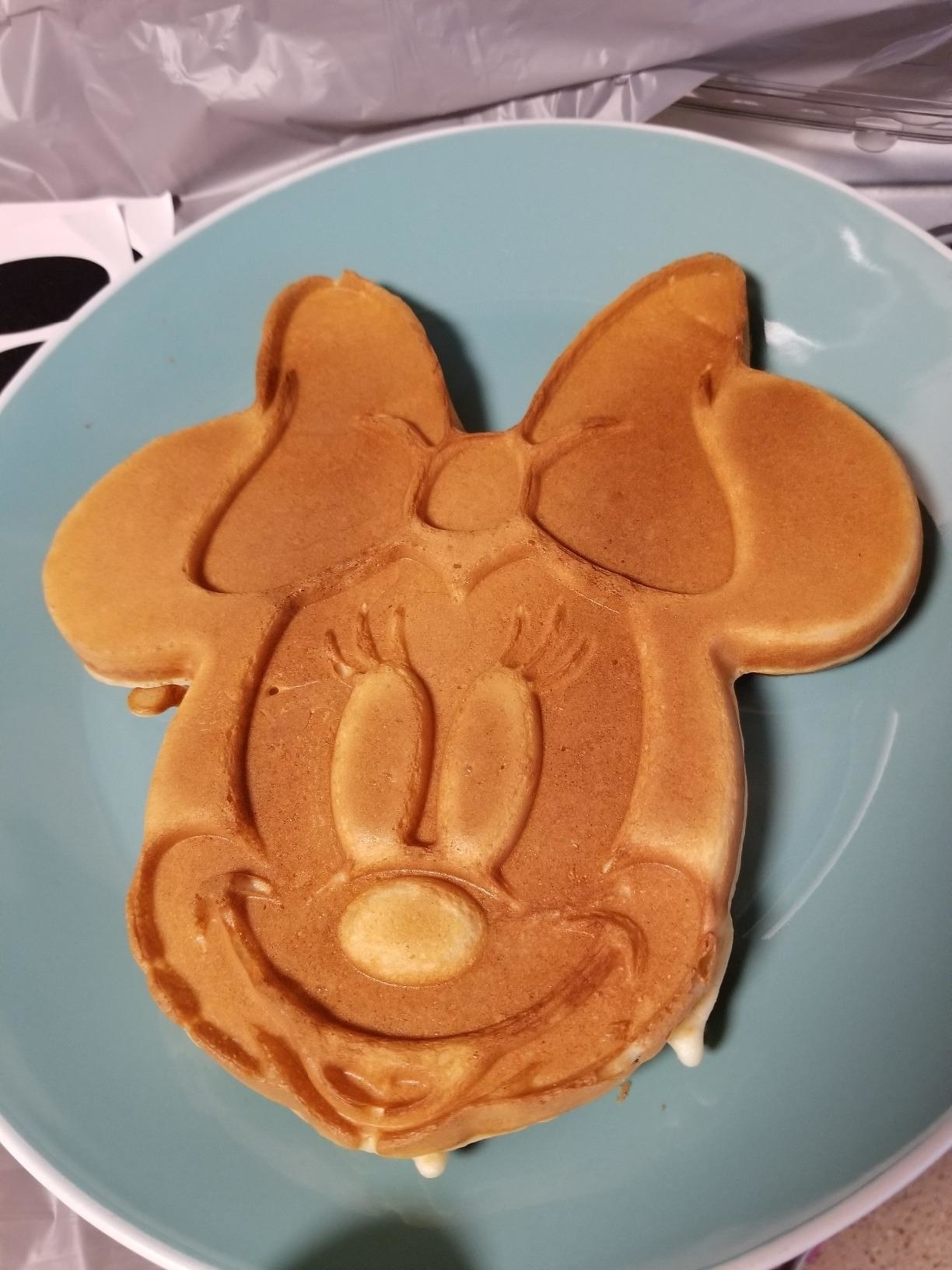 A reviewer showing a waffle in the shape of Minnie Mouse&#x27;s face