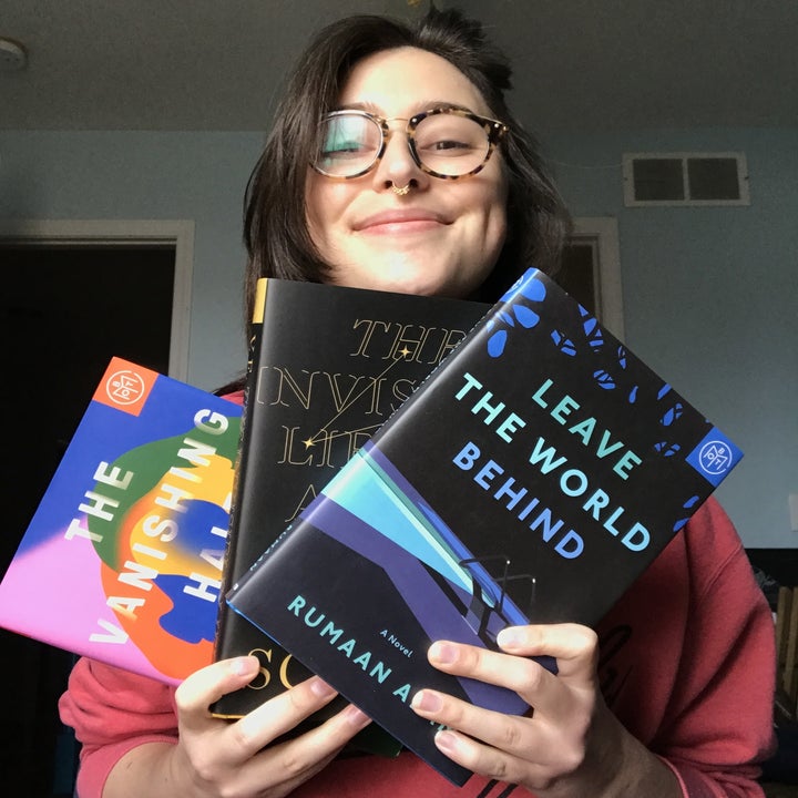 writer holding three hardcover book of the month books