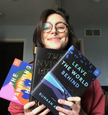 writer holding three hardcover book of the month books