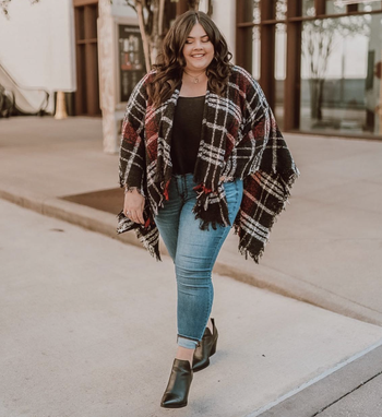 reviewer wearing the poncho with jeans