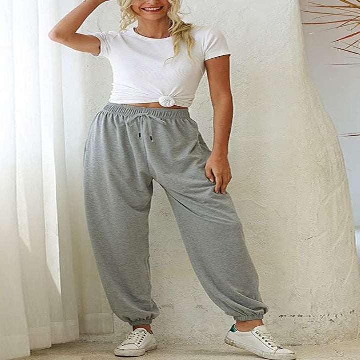 model wearing gray pants with a tied up white shirt