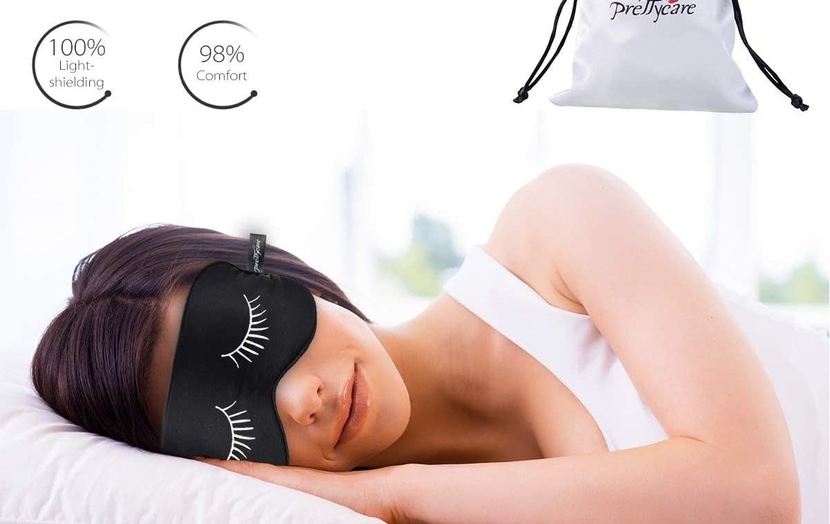 A person sleeps with an eye mask that has eyelashes on it