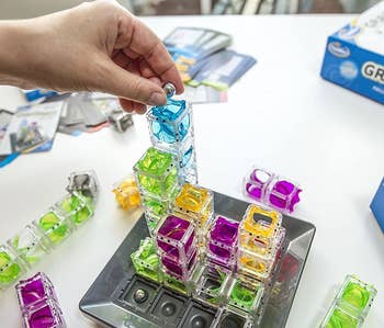 a model placing a marble into the top of clear stacked cubes on the board of the game