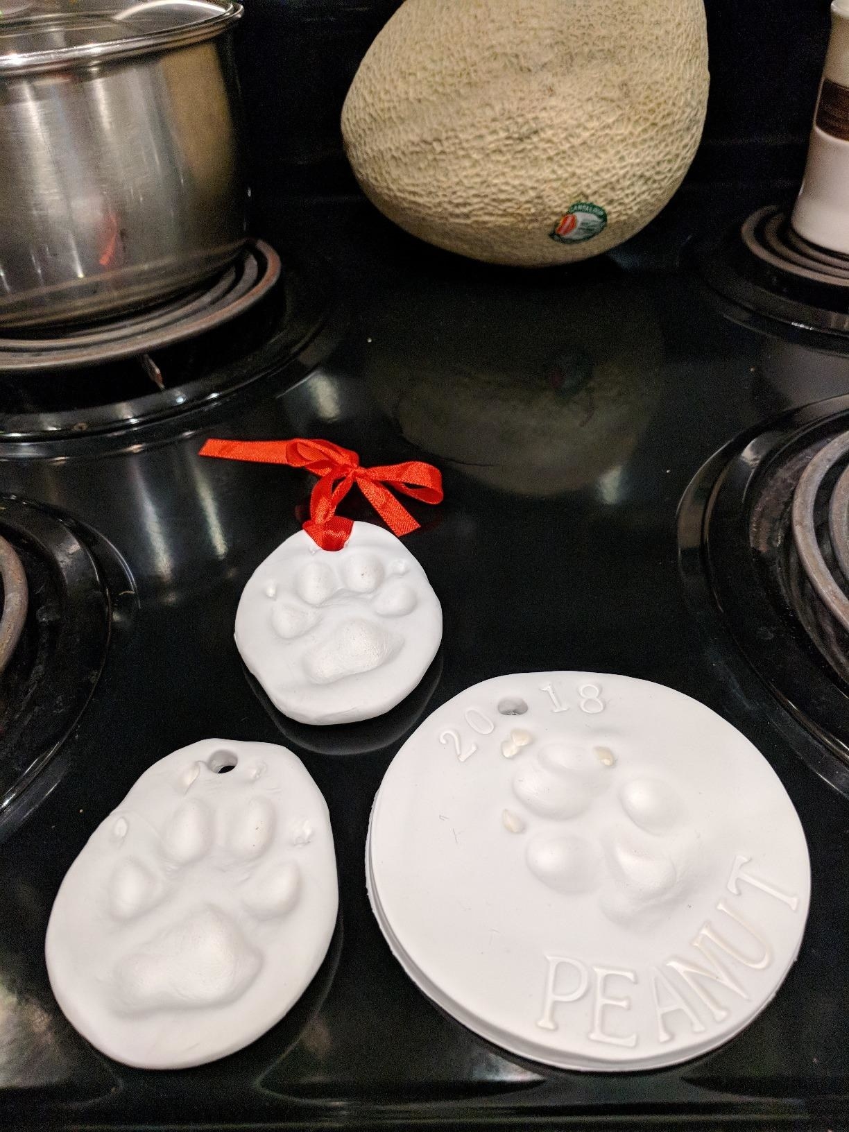 The ornaments, which are white clay and have room for a paw print, name, and ribbon loop for hanging