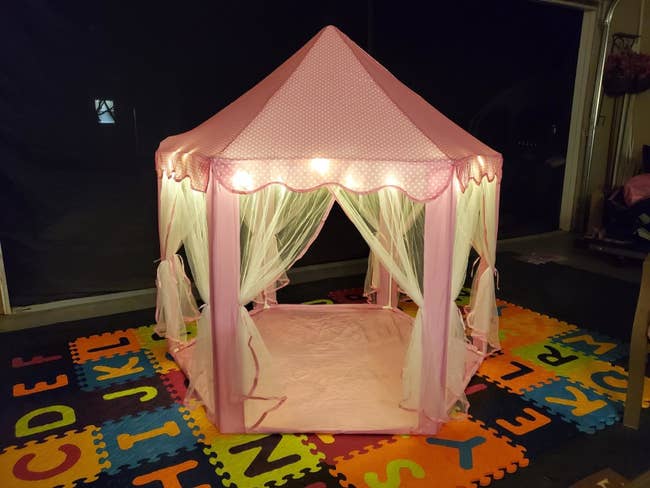 a pink princess castle with tulle drapes and string lights throughout