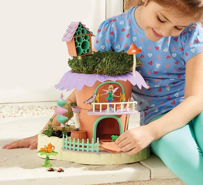 a child model playing with the fairy garden cottage