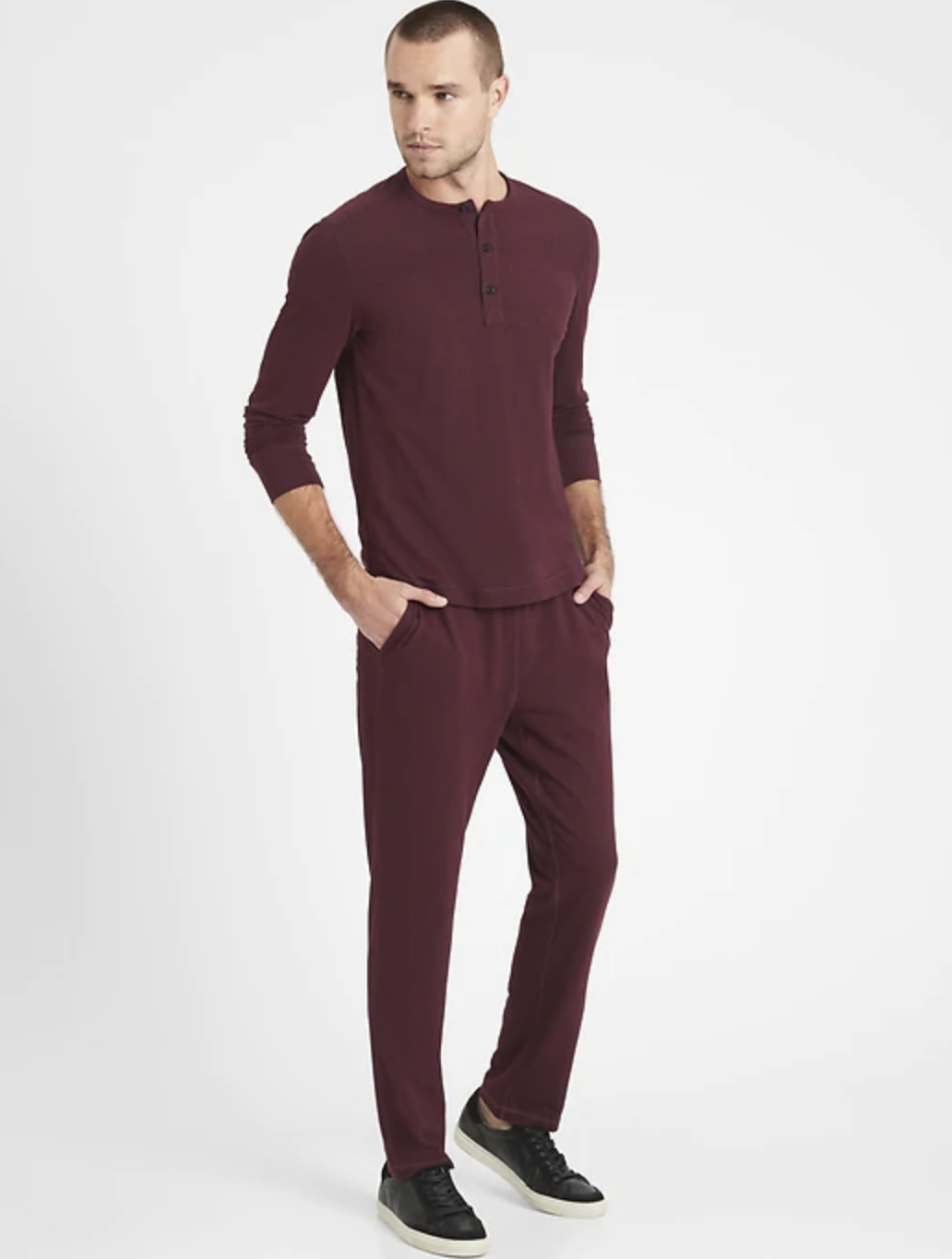 male model wearing a matching burgundy lounge top and bottom with black sneakers