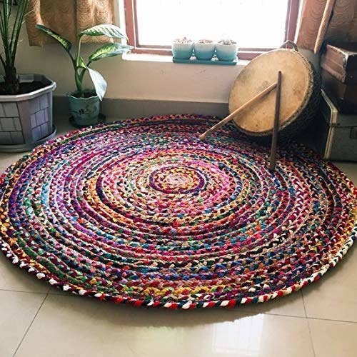 A circular multicoloured jute rug with plants next to it
