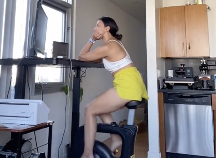 A woman using an exercise bike at her desk