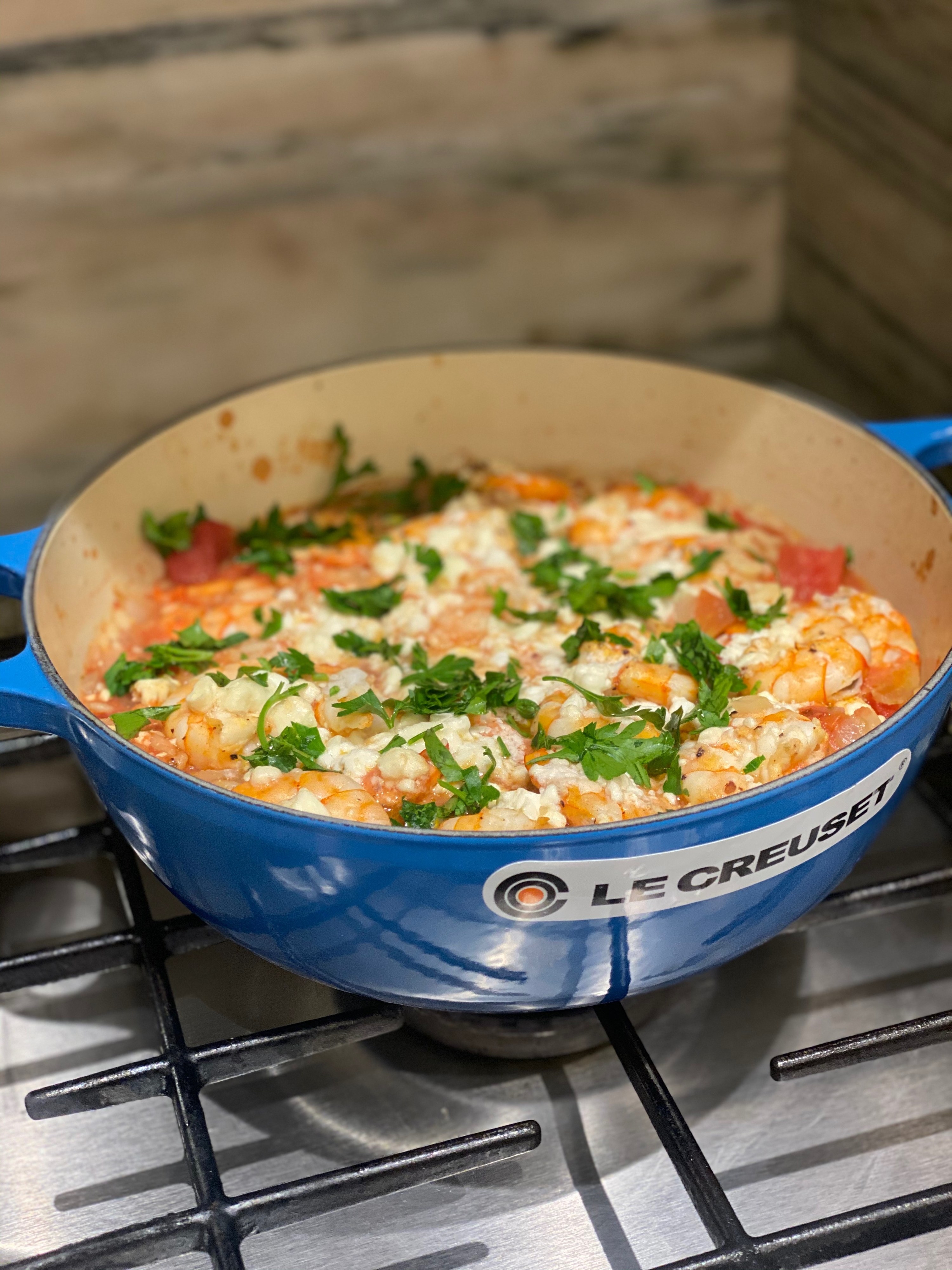 A dutch oven filled with shrimp and feta with orzo and tomatoes.