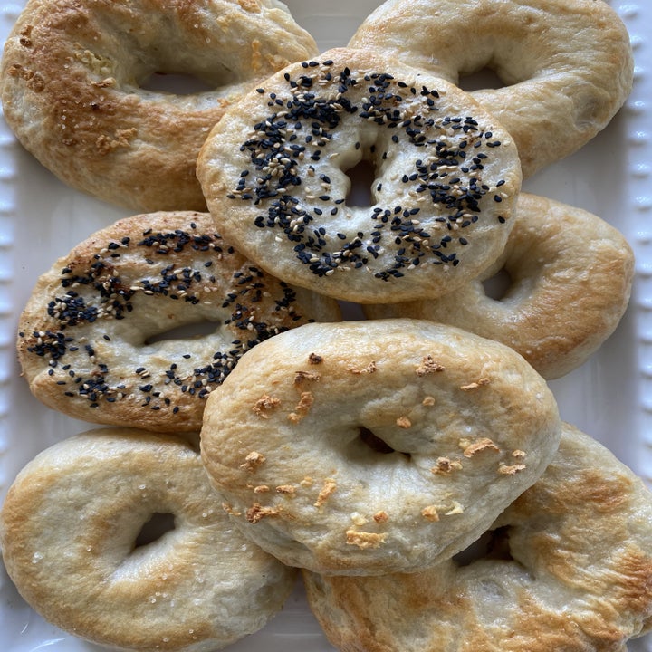 A tray topped with a handful of bagels with different toppings like sesame seeds and garlic.