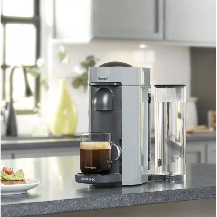 The Nespresso machine with a glass mug full of coffee