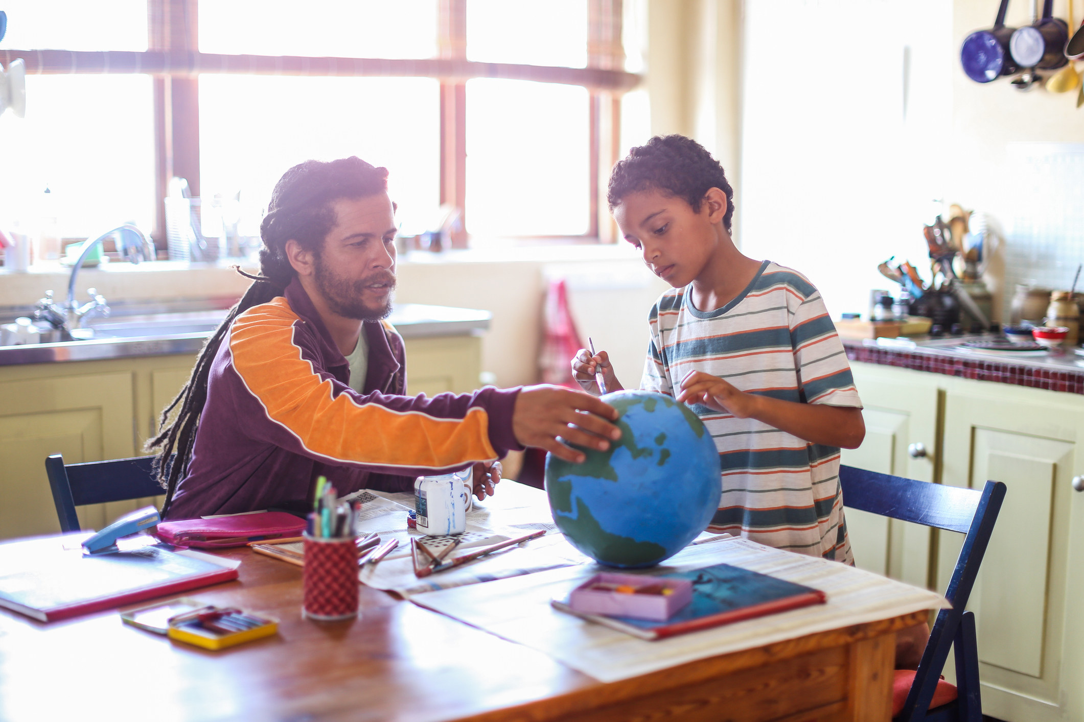 Teacher showing globe to student in classroom. 