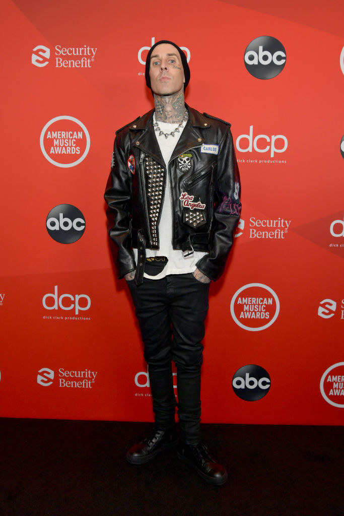 Travis Barker attends the 2020 American Music Awards in. a leather jacket, torn T-shirt, and jeans