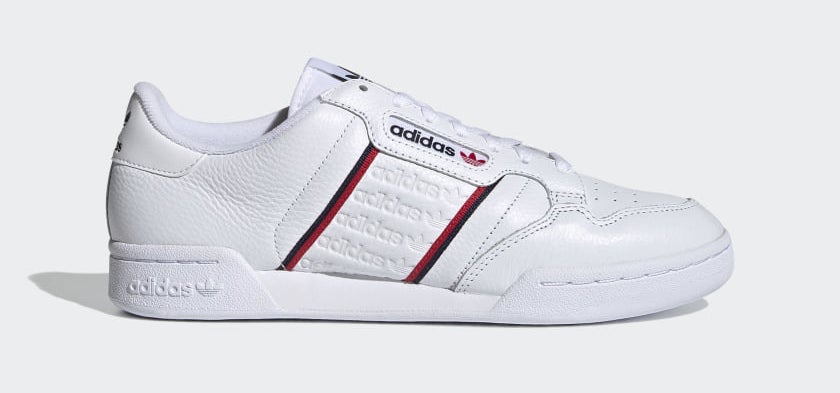 White sneakers with red and blue stripes in the middle and embossed adidas logo in the center