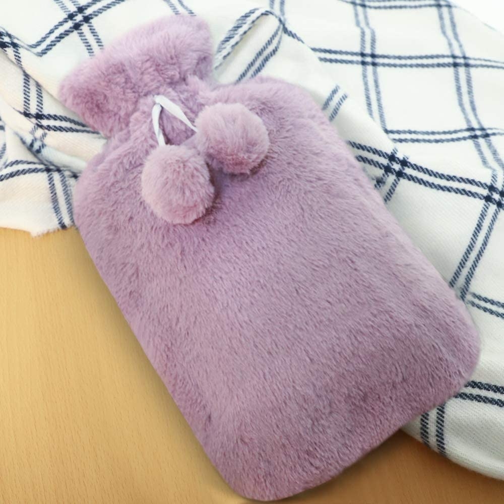 A flatlay of the fuzzy hot water bottle on a flannel blanket