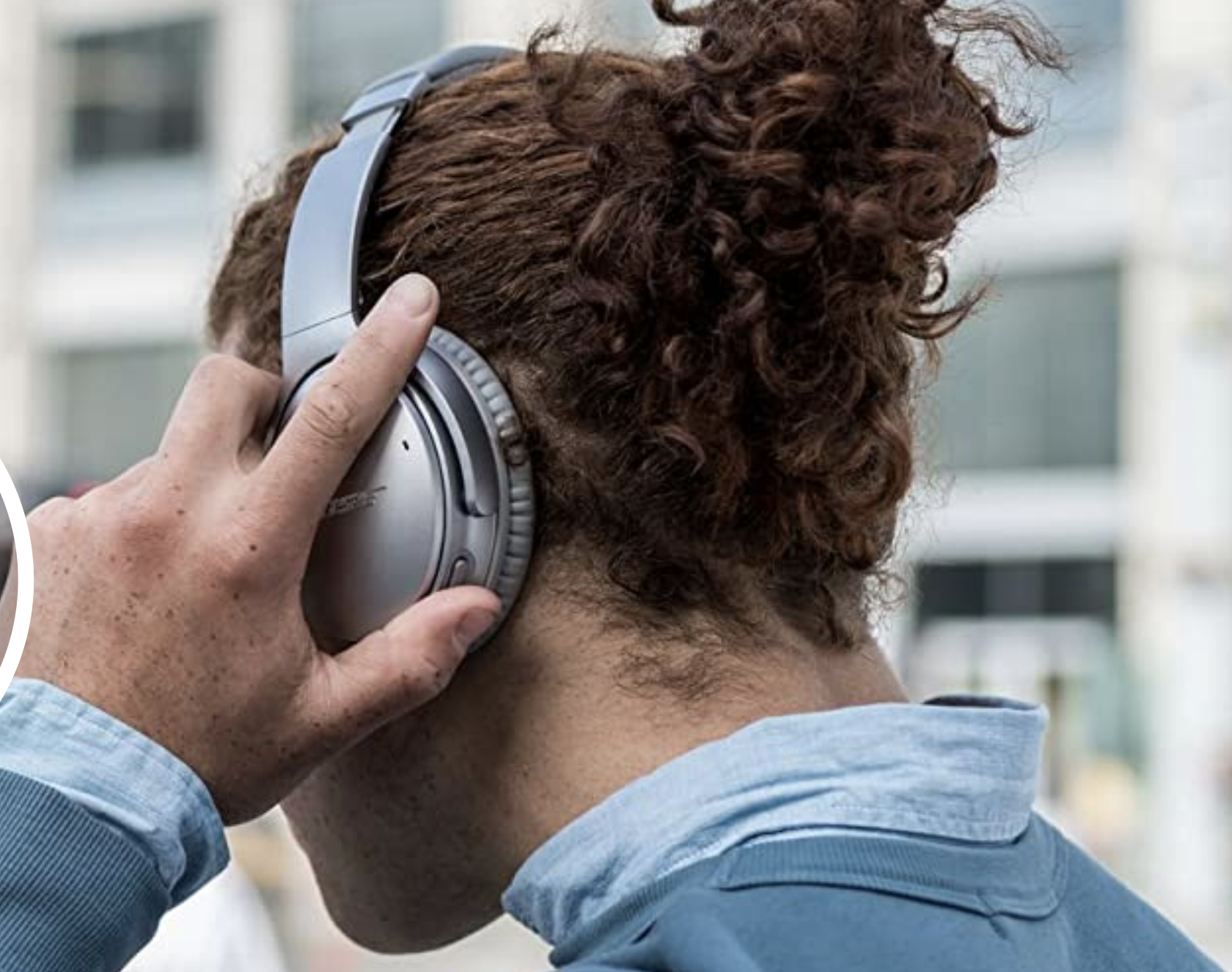 A model wearing a pair of gray over the ear wireless headphones 