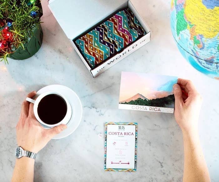 a hand holding a cup of coffee and info card from Costa Rica