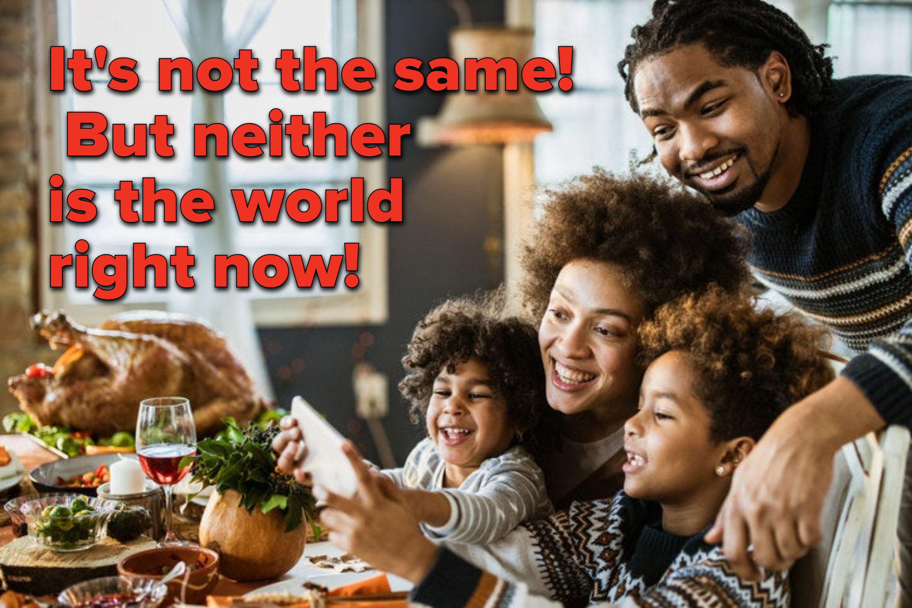 Family sitting down to Thanksgiving dinner holding a phone to face-time. 