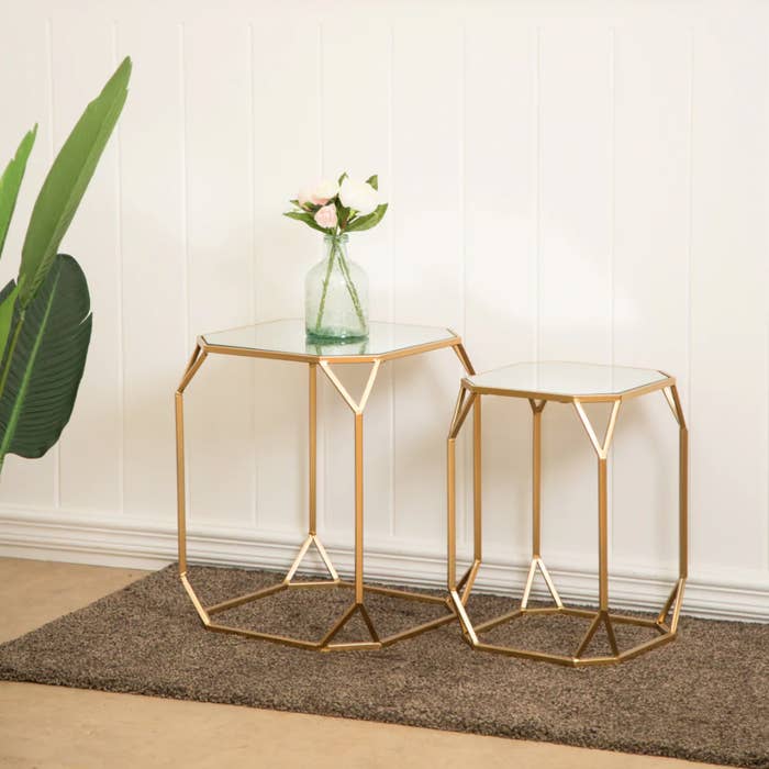 the two hexagon shaped tables with glass tops and gold legs and edges