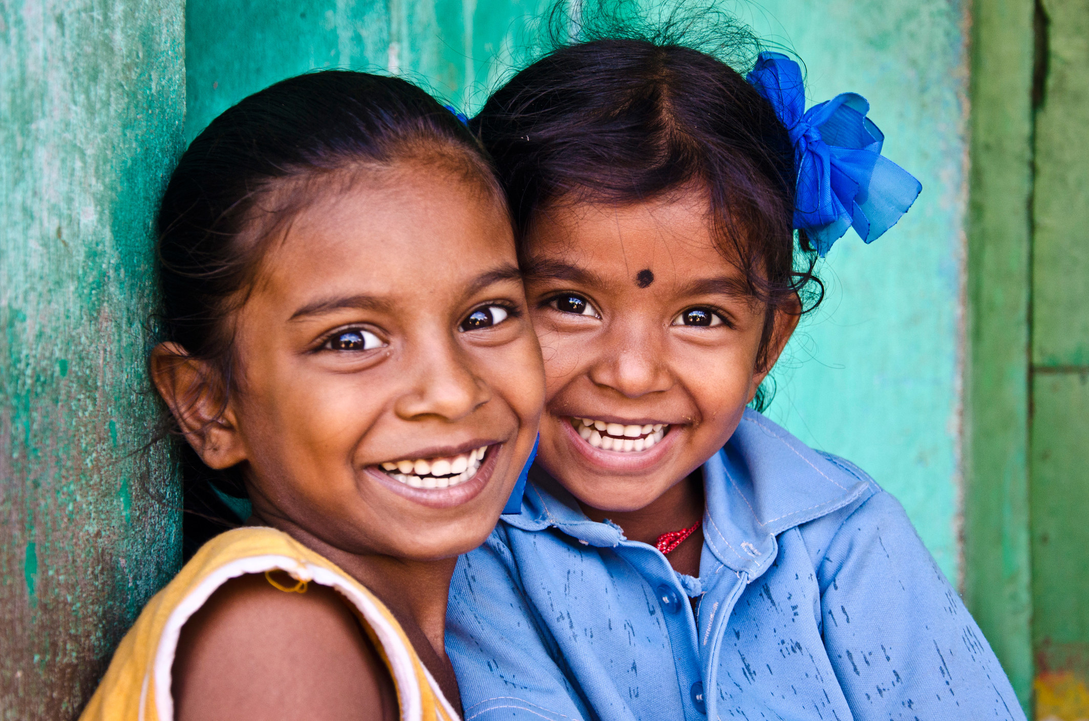 Two kids smiling next to green building. 