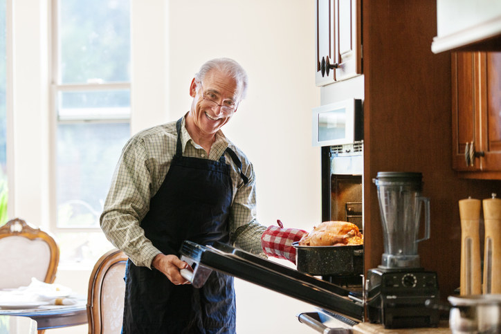 Single senior man cooking turkey