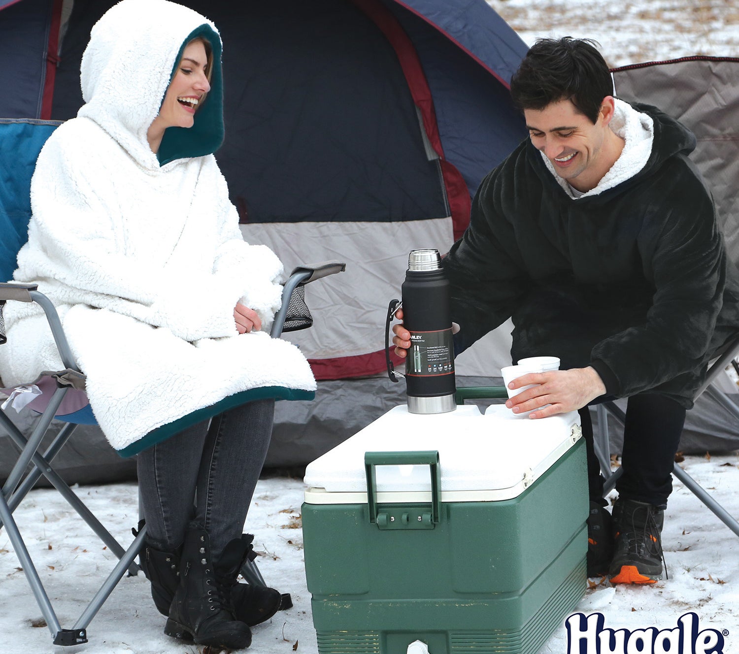 two people wearing huggle hoodie while camping outside in the snow