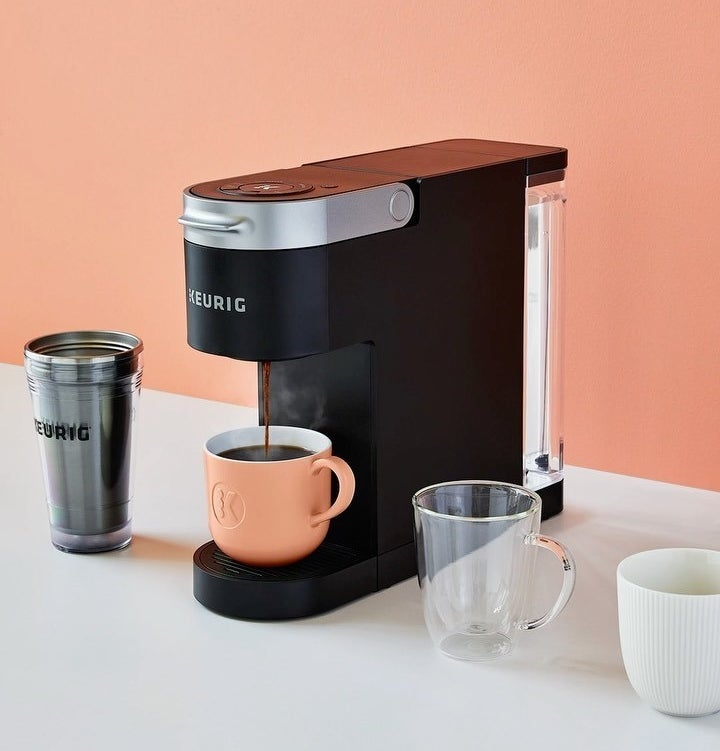 The Keurig slim coffee maker on a counter next to four different coffee mugs