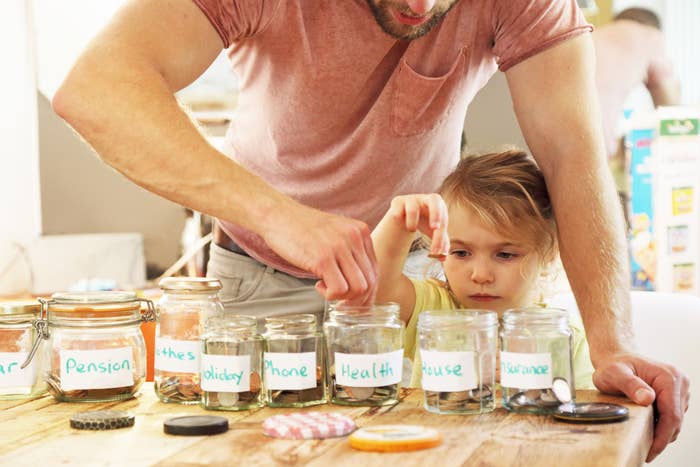 dad with kid putting money in savings jar