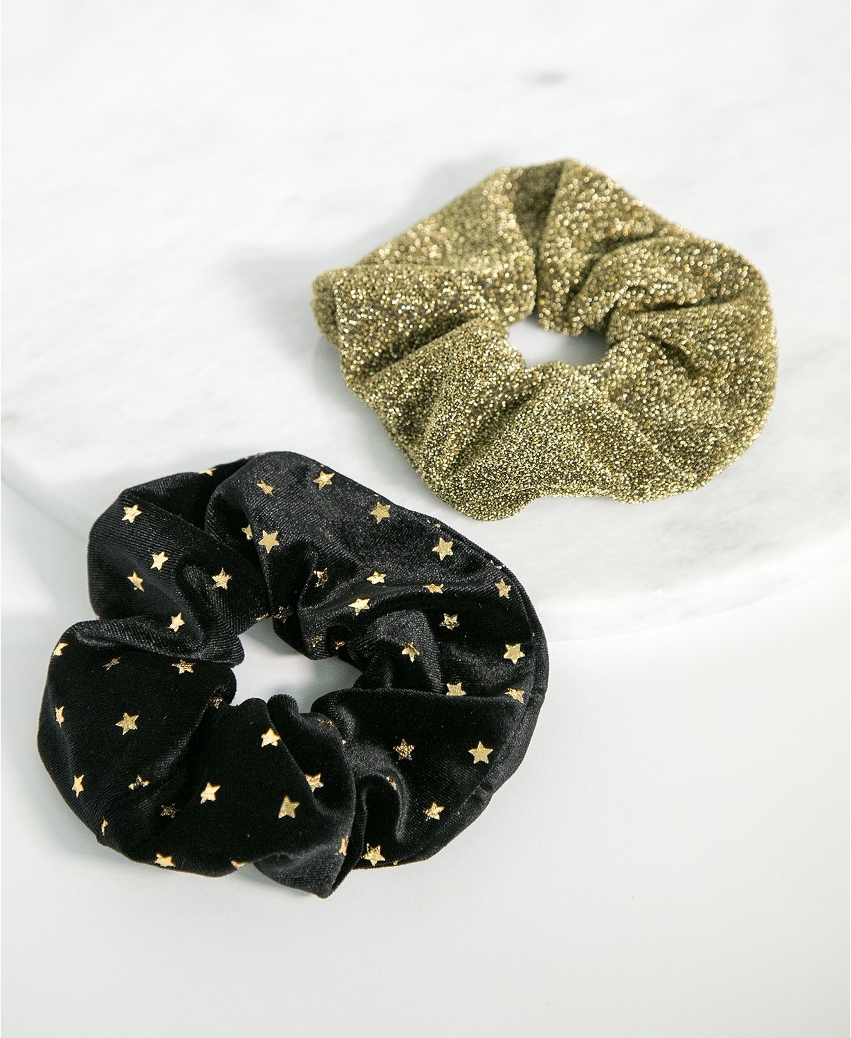 a black velvet scrunchie  with small gold stars on it and a gold shimmery scrunchie