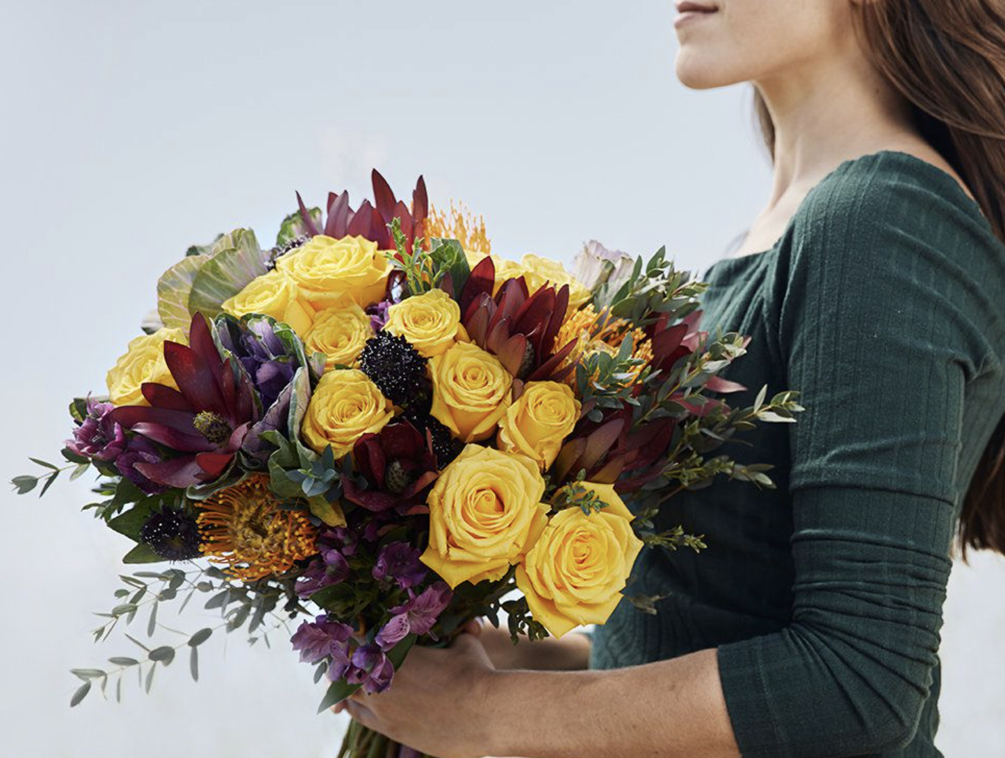 A model holding a bouquet of multicolor roses and other flowers 