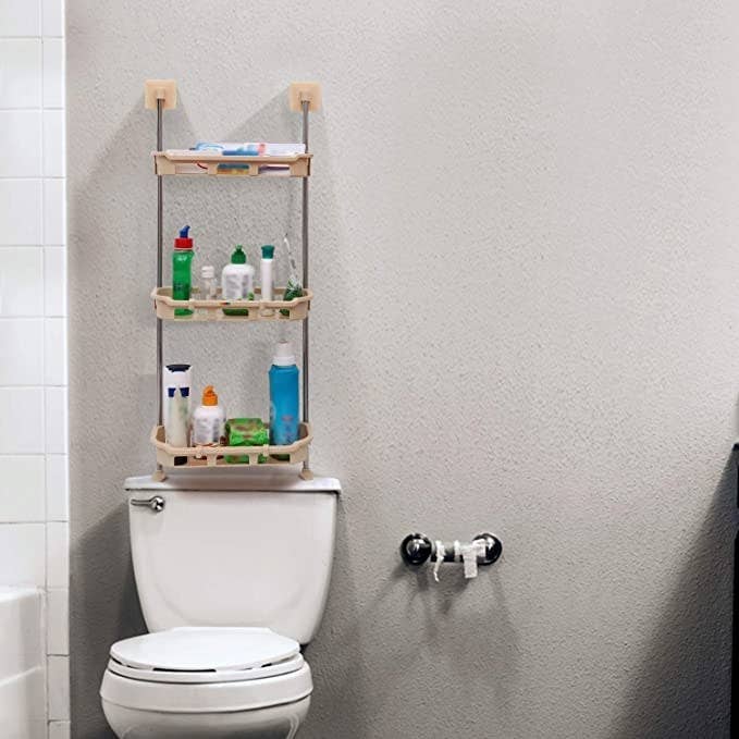 The rack is installed above a toilet. It houses toiletries and other bathroom products.
