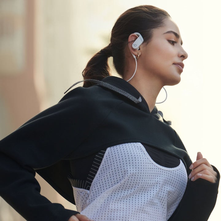 person wearing white powerbeats while running