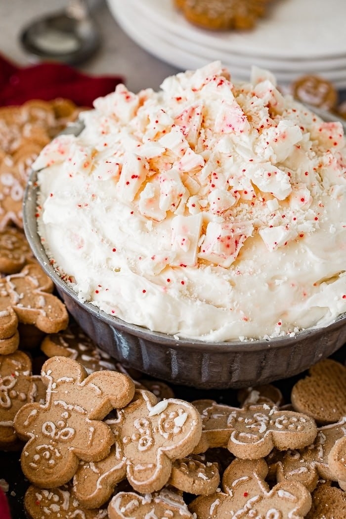 Candy cane white chocolate cheesecake dip in a bowl surrounded by gingerbread cookies