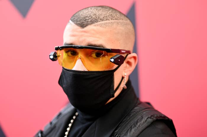 Bad Bunny posing on a red carpet wearing glasses and a face mask