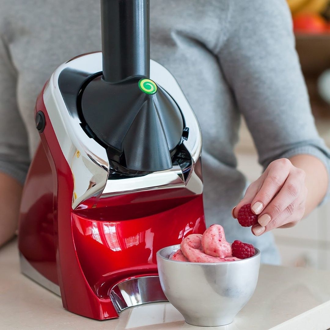 A person making raspberry ice cream with the Yonanas machine