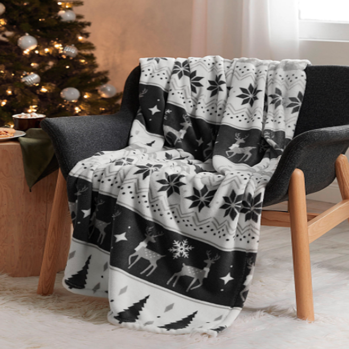A throw blanket with christmas trees and reindeer on it