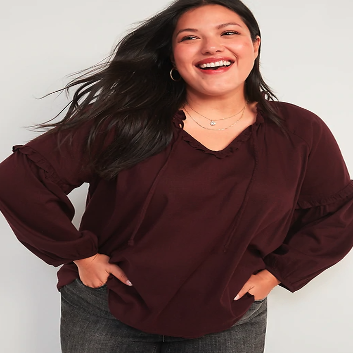 Model wearing a burgundy blouse with a tie front
