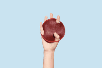 gif of a model&#x27;s hand rotating while holding the Boie body scrubber with their fingers