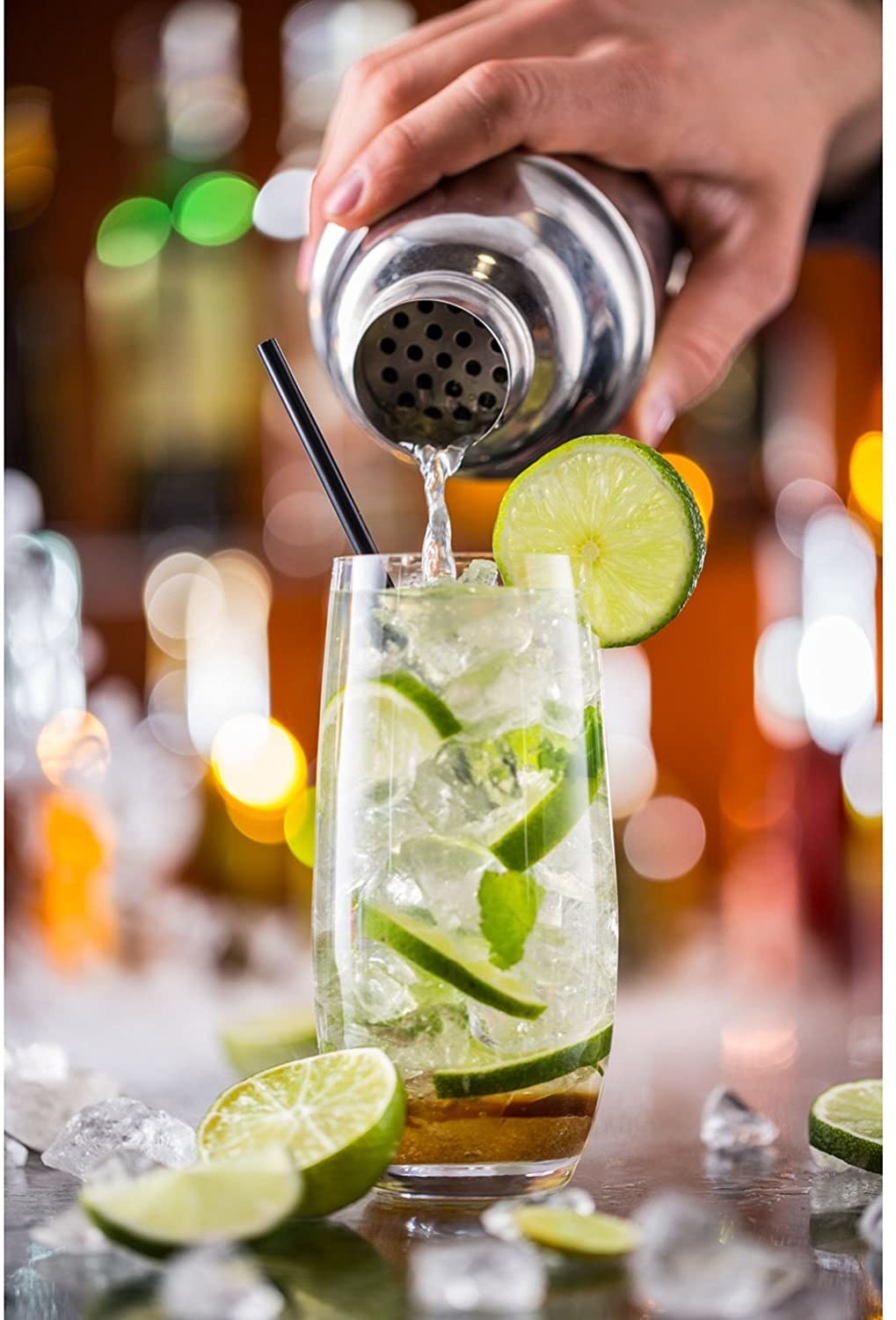 A person pours a drink into a class from a cocktail shaker