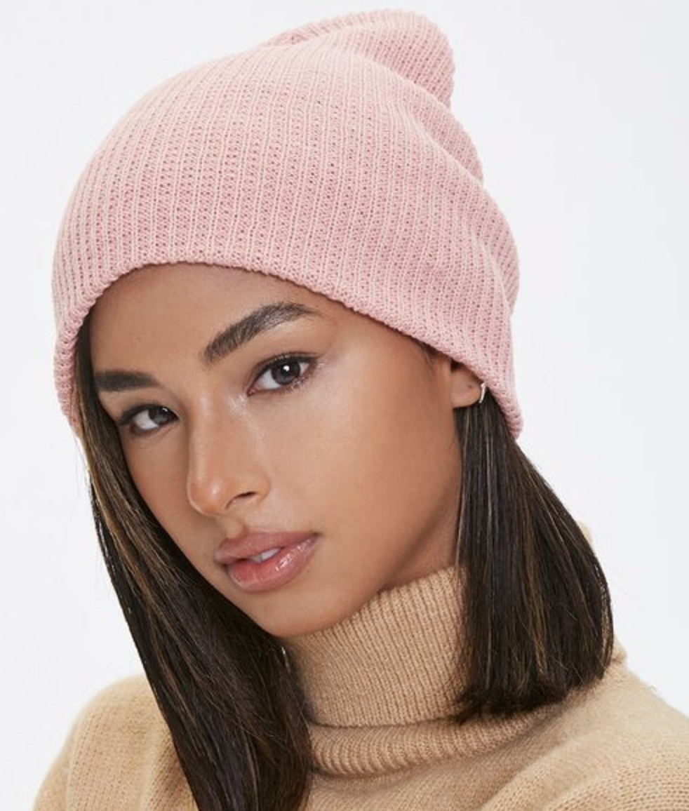 Model is wearing a light pink ribbed knit beanie and a turtleneck sweater