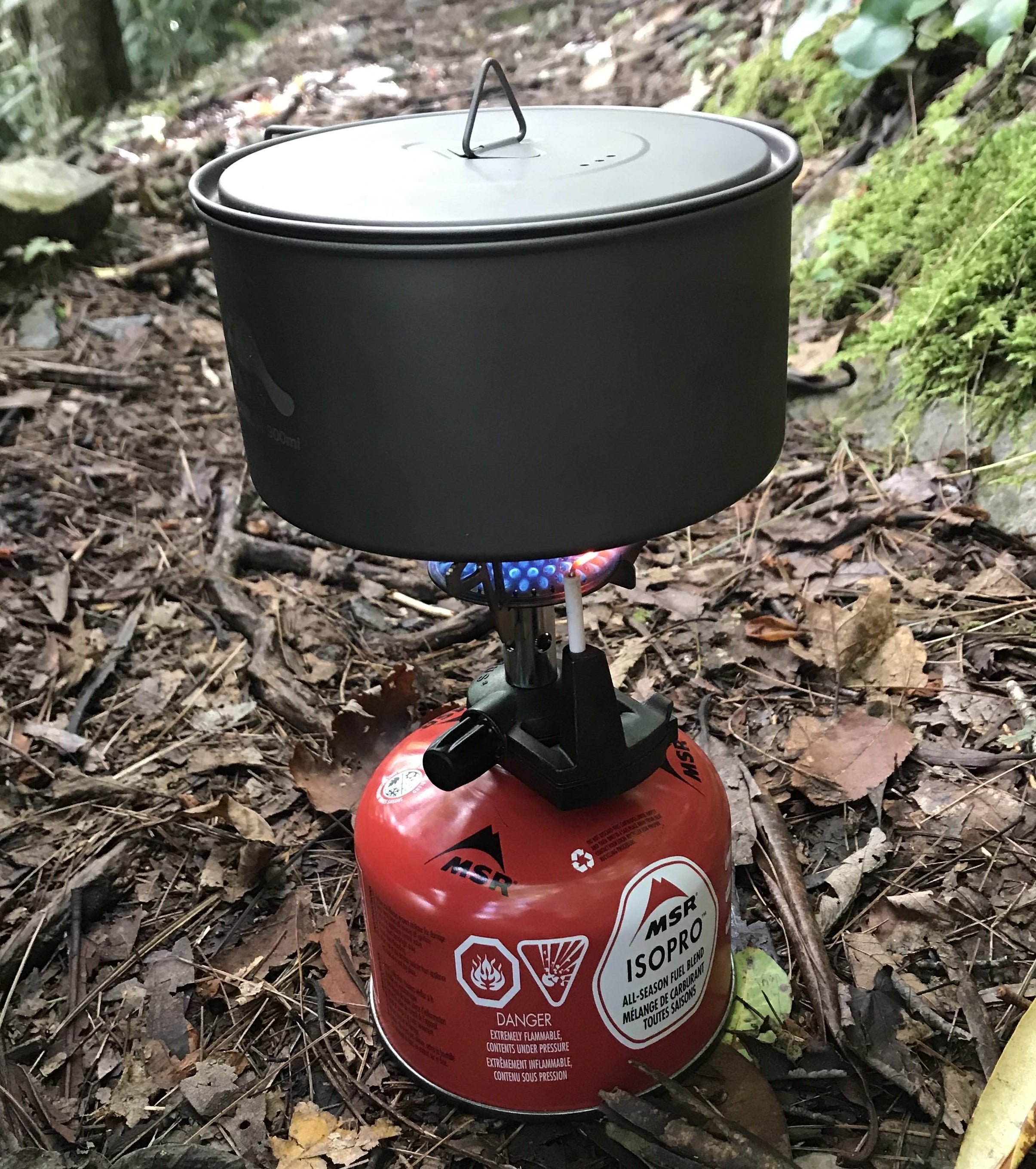 the writer&#x27;s pot and lid sitting on a small lit camp stove