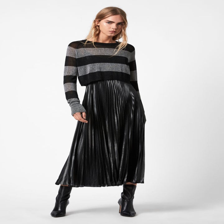 A model wearing the slightly sheer silver and black sweater over the midi length pleated slip dress