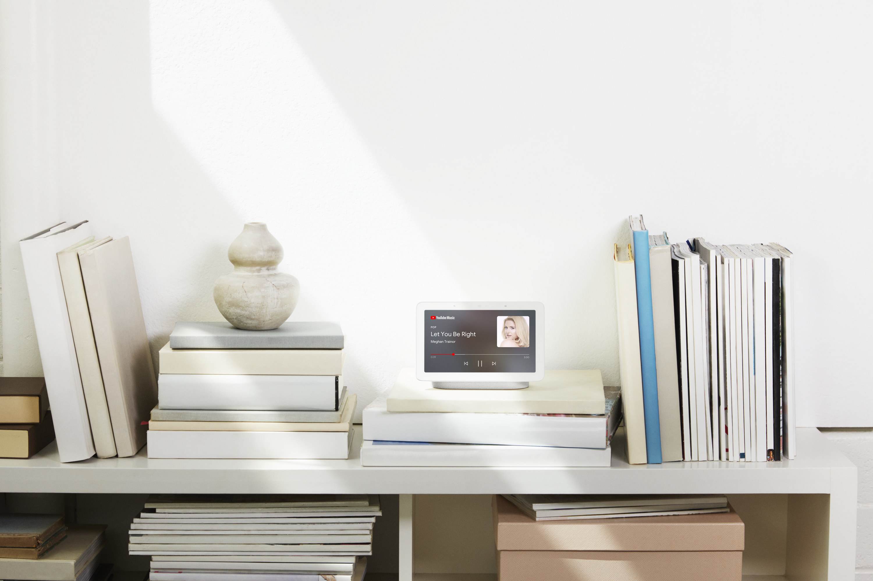 Nest Hub from Google on shelf with books. 