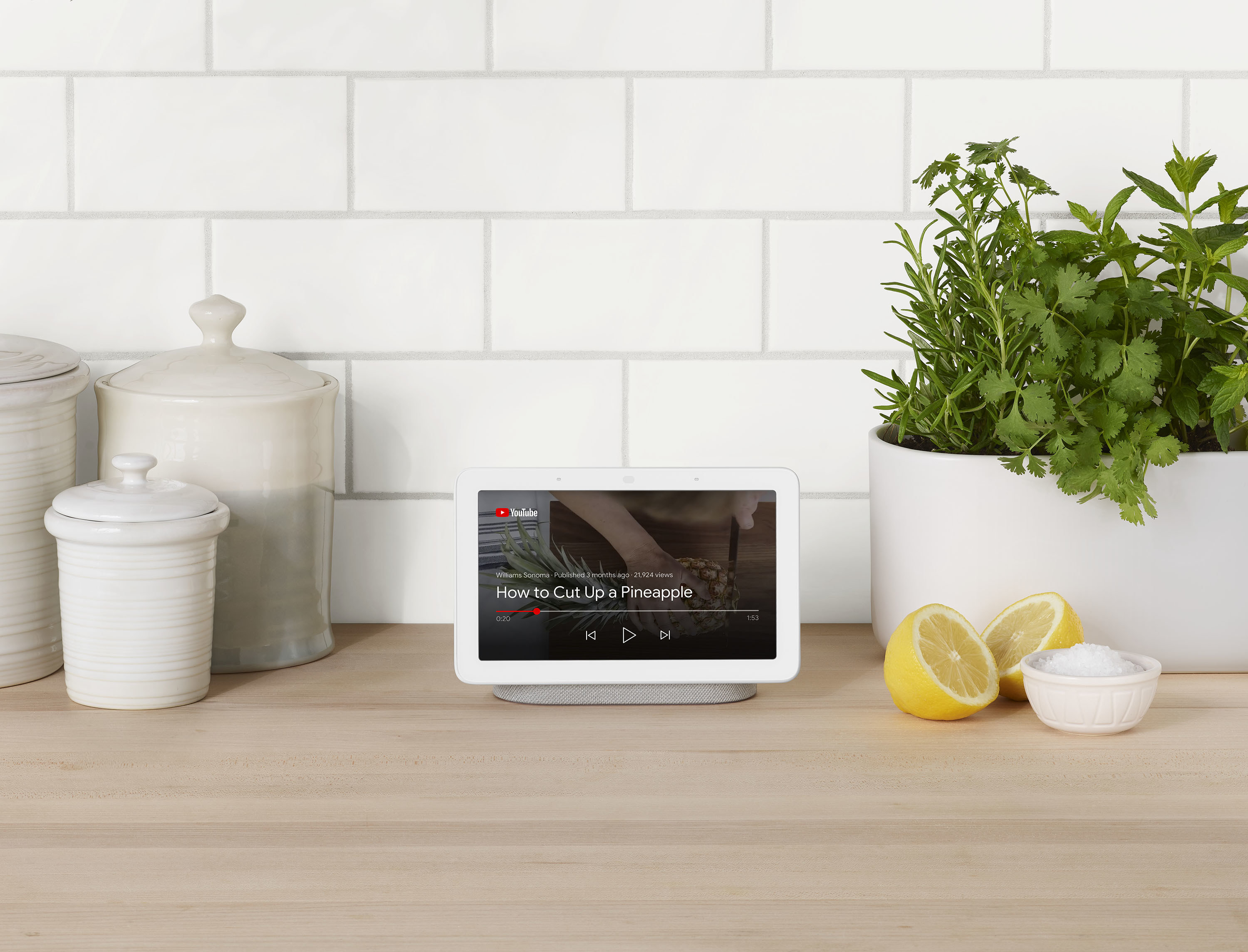 Nest Hub on countertop with lemons and herbs with video on screen about how to cut a pineapple. 