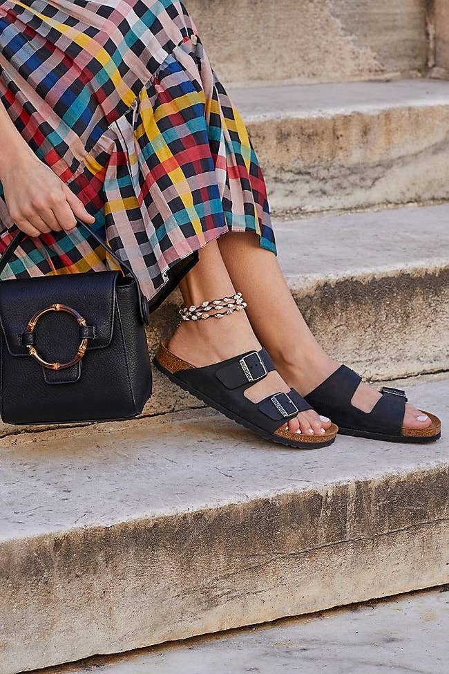 A model wearing the two-strap arizona birkenstocks in black with their cork foootbed