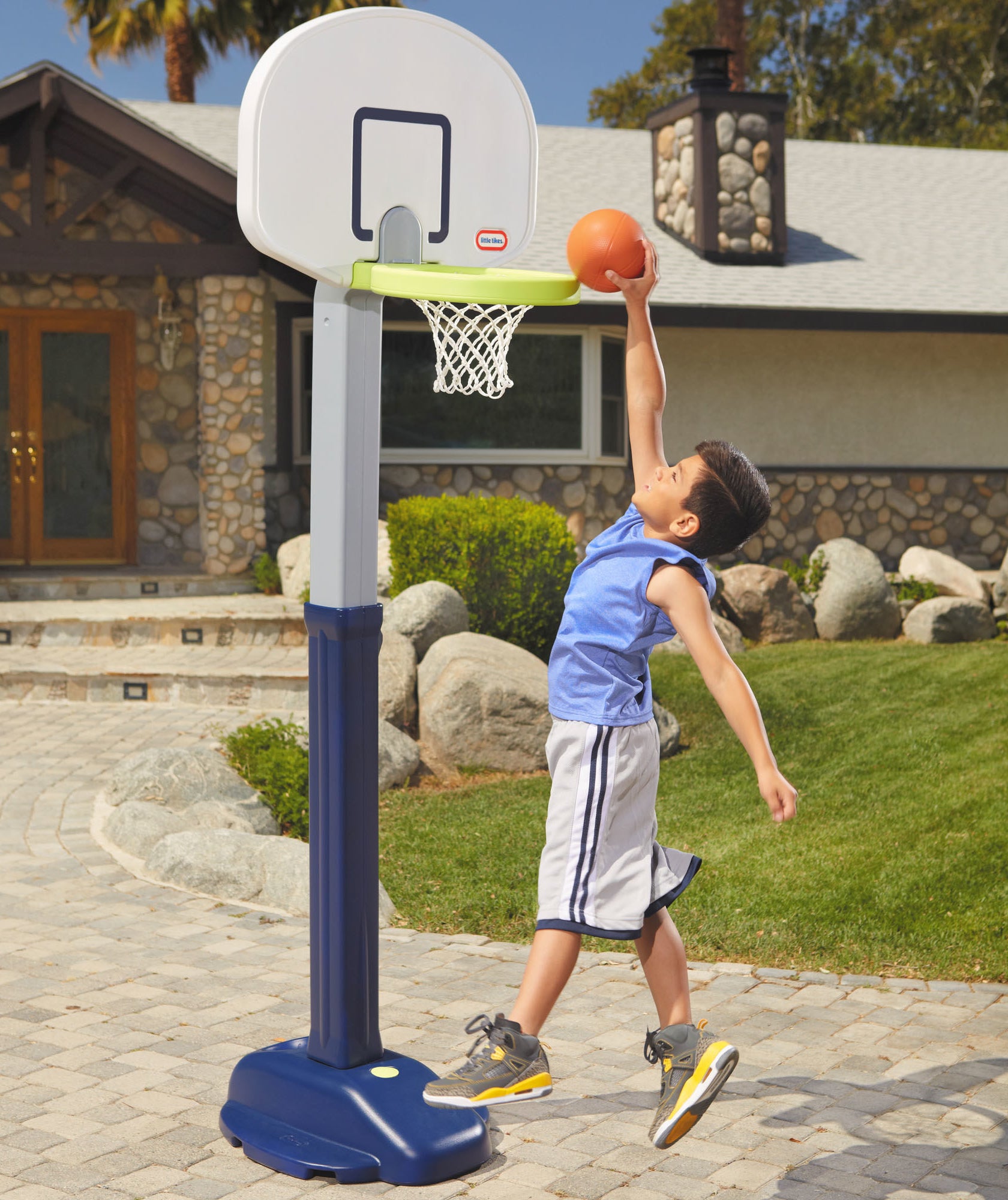 child slam dunking a small basketball into a little tikes basketball hoop