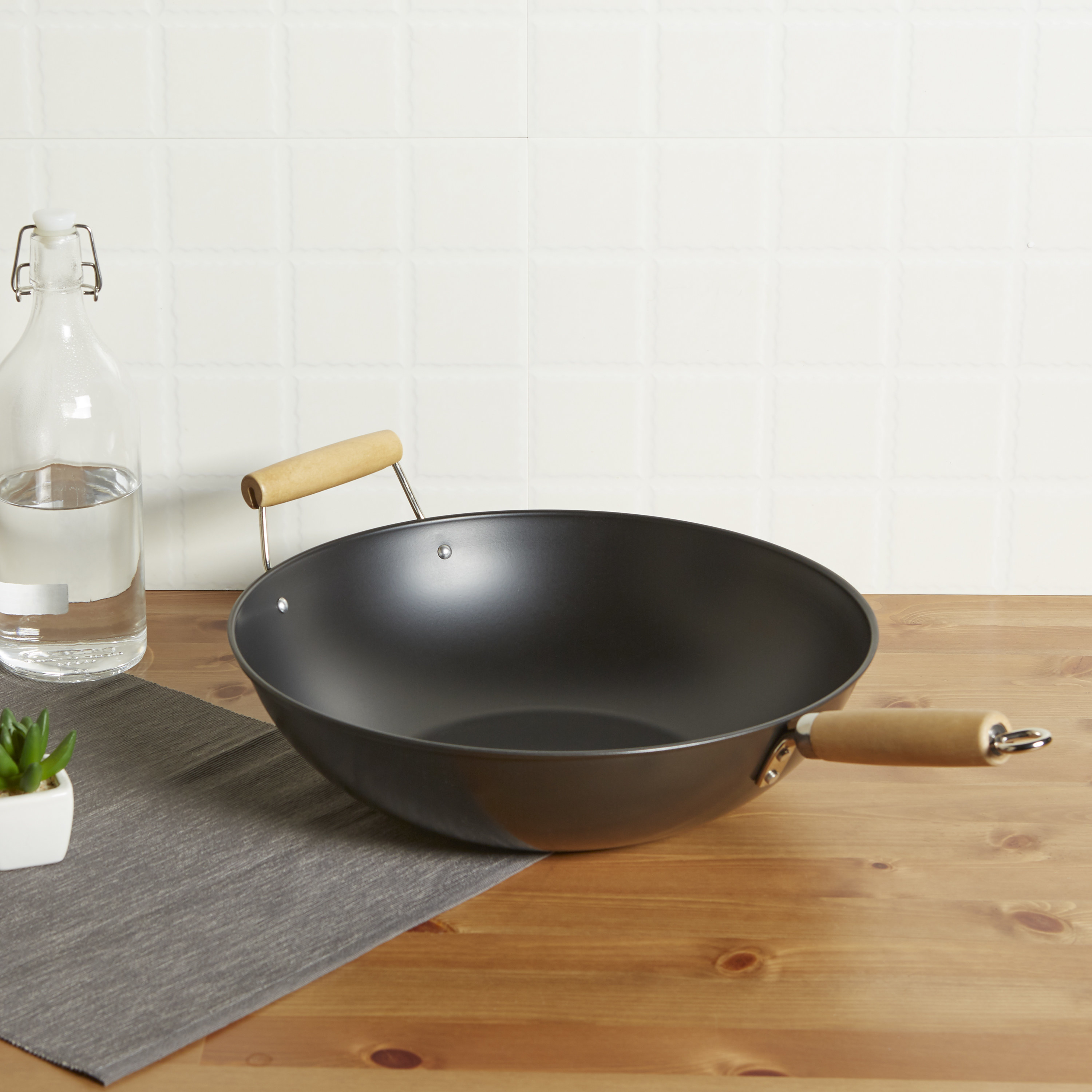 black wok with a wooden handle sitting on a kitchen counter